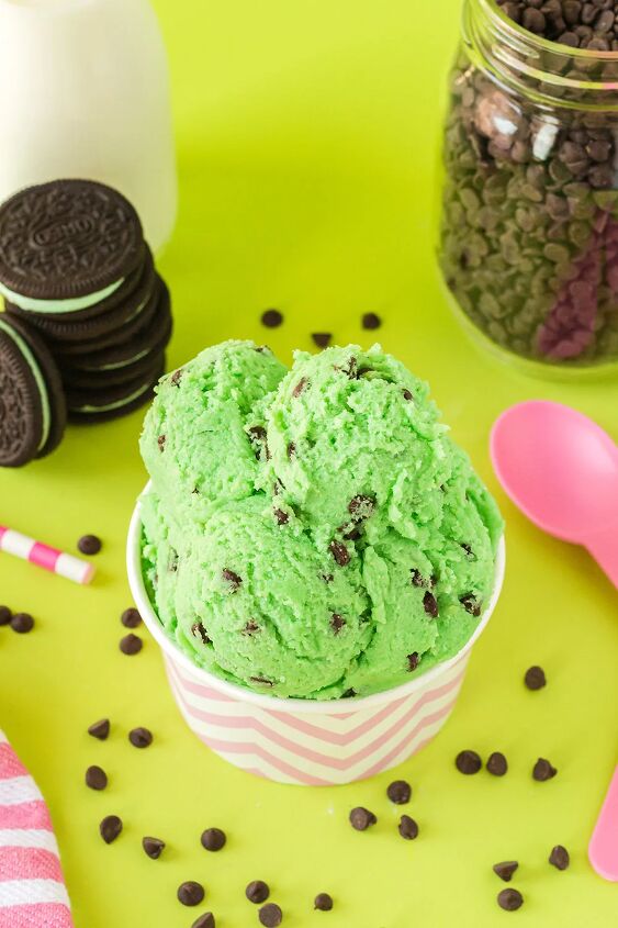mint chip edible cookie dough, Scoops of mint chip dough in a pink cup with OREOs chips milk and pink spoons on a green background