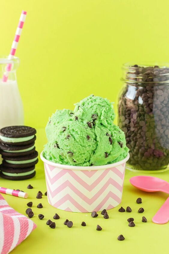 mint chip edible cookie dough, Pink cup of mint chip cookie dough with cookies milk pink spoons and chips on a green background