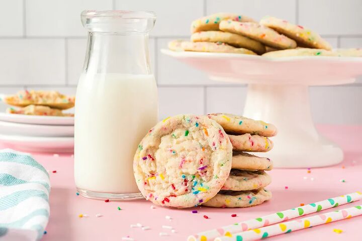 soft and chewy funfetti cookies recipe, Funfetti cookies on a stand stacked in front of the stand and next to a glass of milk