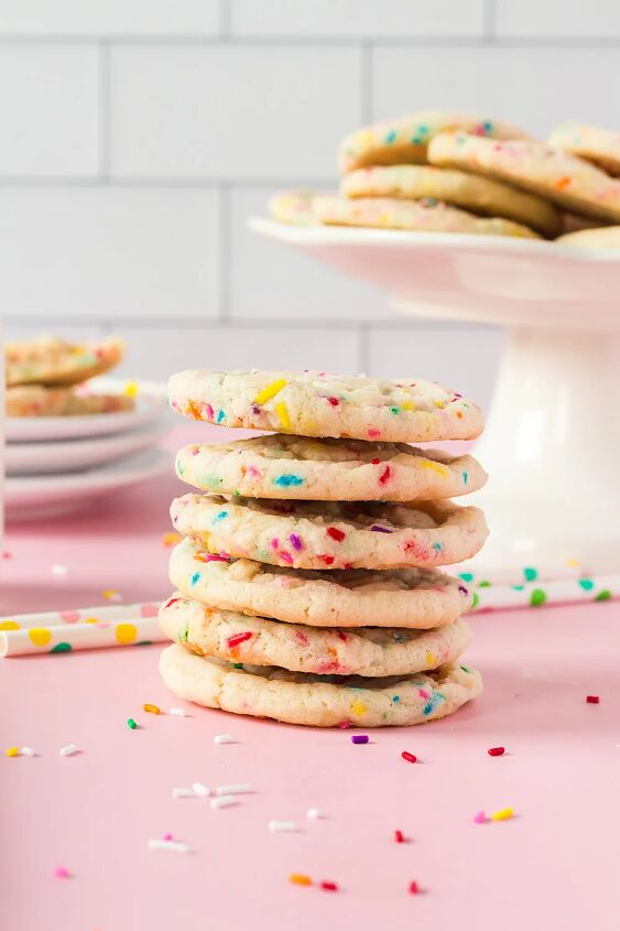 soft and chewy funfetti cookies recipe, Stack of sugar cookies with rainbow sprinkles next to cookies on a stand and plates