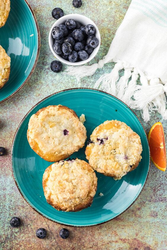 blueberry orange muffins with crunchy oat topping, Overhead image of three blueberry muffins on a blue plate