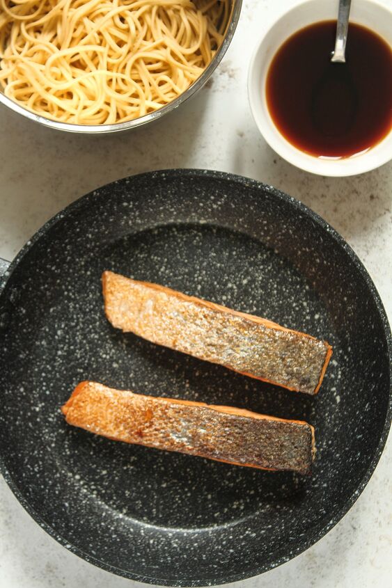 teriyaki salmon noodles, Two cooked salmon fillets in a frying pan on a white background