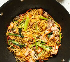 teriyaki salmon noodles, A wok containing the cooked veggies noodles and salmon tossed in the sauce on a white background