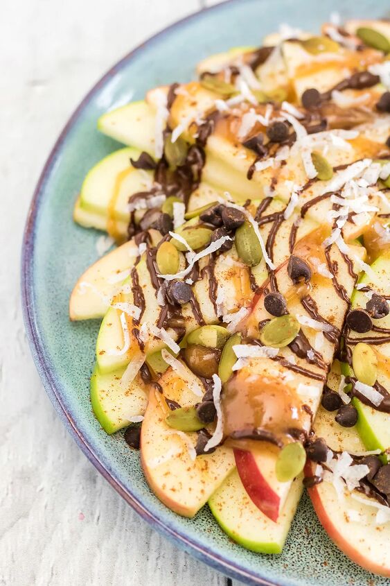 crunchy apple nachos with sweet and salty toppings, Green and red apple slices on a plate topped with chocolate caramel nuts and toppings