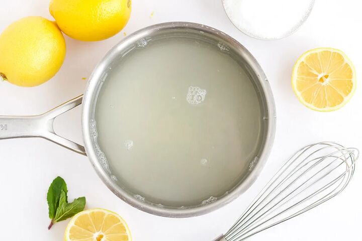 easy and refreshing lemon popsicles, Water and sugar in a pan surrounded by lemons sugar and a whisk