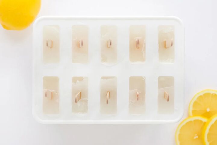 easy and refreshing lemon popsicles, Frozen ice pops in the mold with lemon slices on the table