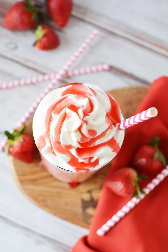 delicious copycat strawberry frappuccino recipe, Overhead shot of strawberry syrup on top of whipped cream in a glass of a pink blended drink