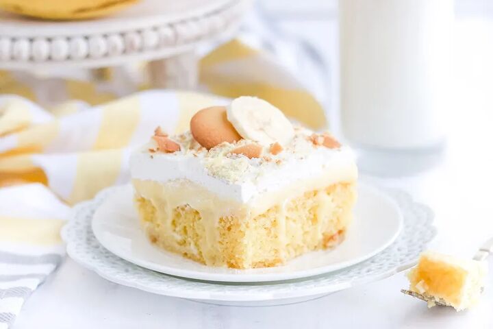 light and creamy banana poke cake recipe, Yellow cake on a white plate on a white table with bananas and cookies