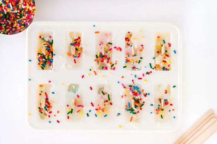 happy funfetti cake batter popsicles, Sprinkles on top of popsicles in a freezing container