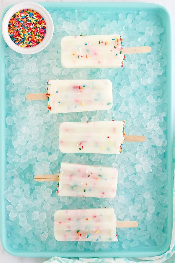 happy funfetti cake batter popsicles, Cake batter pops in a row sitting on ice on a blue tray