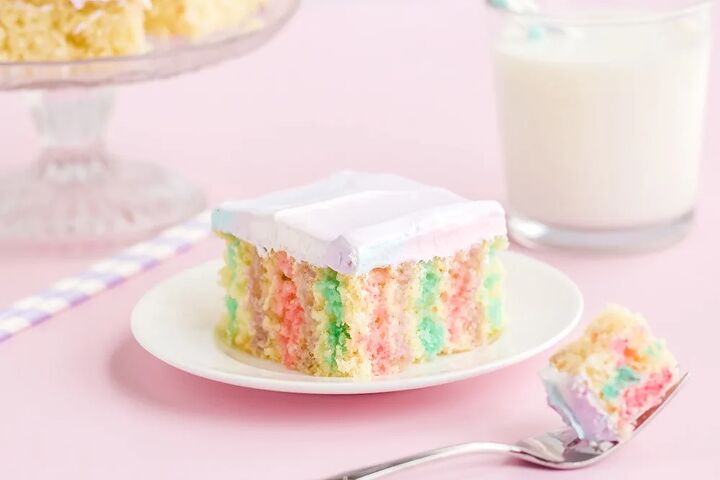 rainbow unicorn poke cake recipe, Rainbow poke cake on a white plate on a pink table with milk