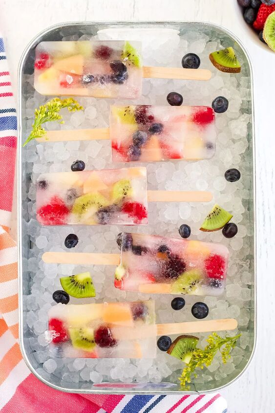rainbow fruit popsicles, Fruit pops lined up on a bed of nugget ice with fruit in a tray