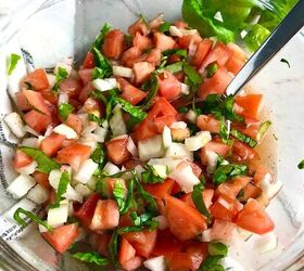 Tomato and onion salad in clear bowl on counter with towel It has diced tomato diced onion basil and vinegar
