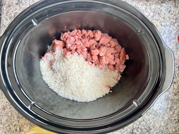 ground pork slow cooker casserole, Crockpot insert on counter with raw ground port and uncooked rice added for Ground Pork Slow Cooker Casserole