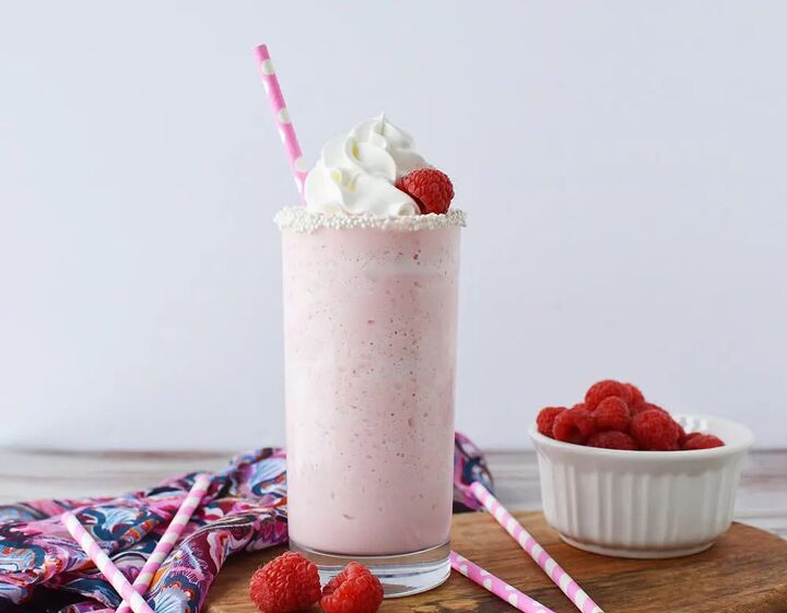 copycat raspberry cotton candy frappuccino recipe, Pink cotton candy blended drink in a glass topped with whipped cream and raspberries