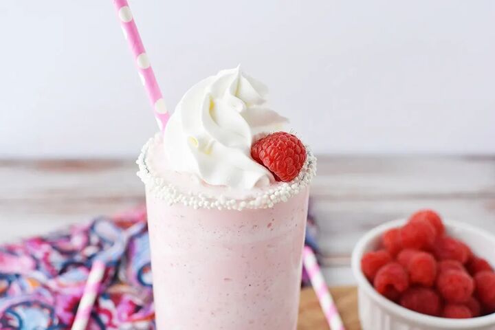 copycat raspberry cotton candy frappuccino recipe, Glass of a pink raspberry blended drink with whipped topping and fresh raspberries