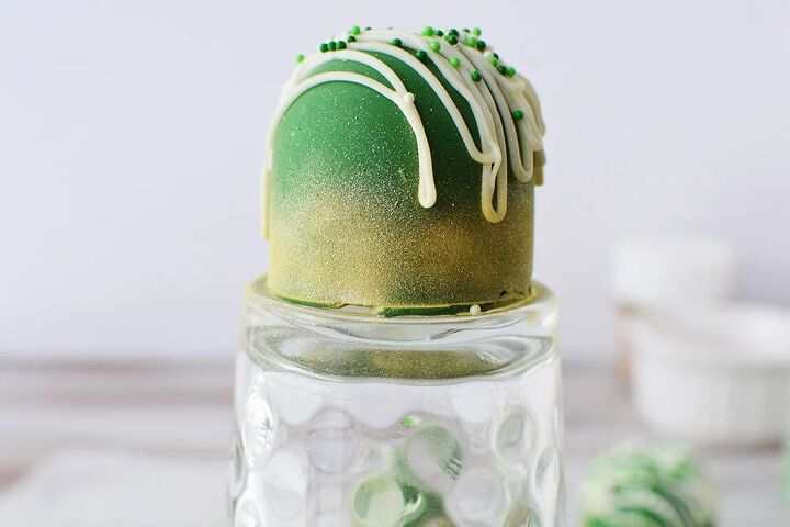 glittery green hot chocolate bombs recipe, Green candy sitting on a glass after being sprayed with edible gold glitter spray