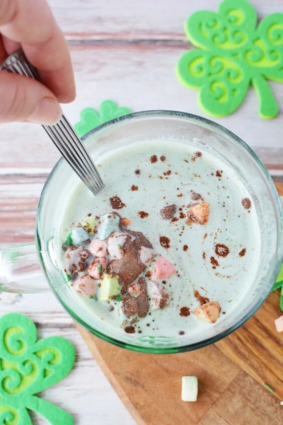glittery green hot chocolate bombs recipe, Stirring green hot chocolate with rainbow marshmallows