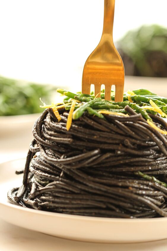 black squid ink pasta, Close up of a plate of black squid ink pasta topped with samphire and lemon zest