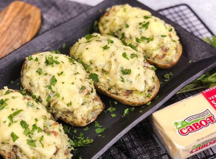 air fryer twice baked loaded potatoes, Side shot of Air Fryer Twice Baked Loaded Potatoes garnished with parsley on a black serving platter with a block of Cabot Seriously Sharp Cheddar Cheese in bottom right