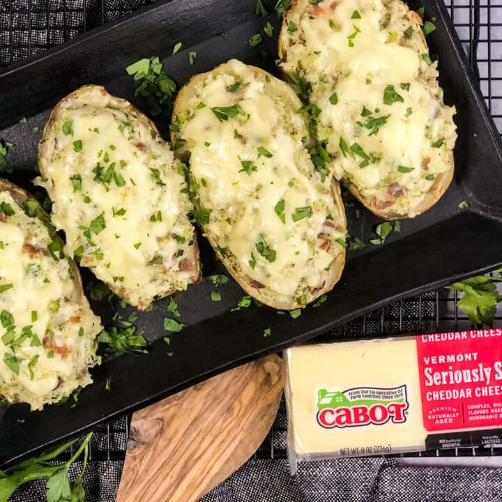 air fryer twice baked loaded potatoes, Overhead shot of Air Fryer Twice Baked Loaded Potatoes garnished with parsley on a black serving platter with a block of Cabot Seriously Sharp Cheddar Cheese in bottom right