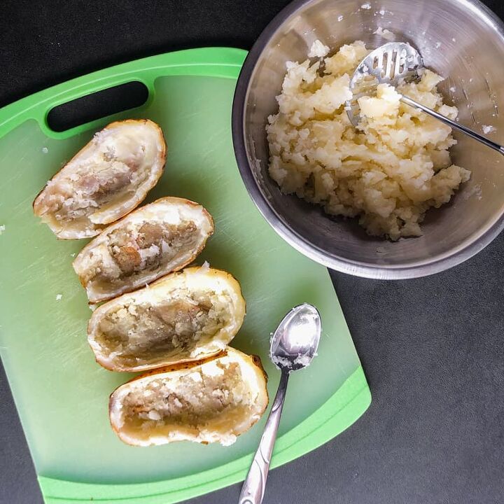 air fryer twice baked loaded potatoes, Scooped out potato halves on a green cutting board next to a bowl of the mashed potato flesh