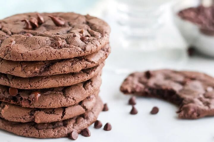 chewy brownie mix cookies recipe, A stack of brownie cookies with a cookie missing a bite next to chocolate chips on a white table