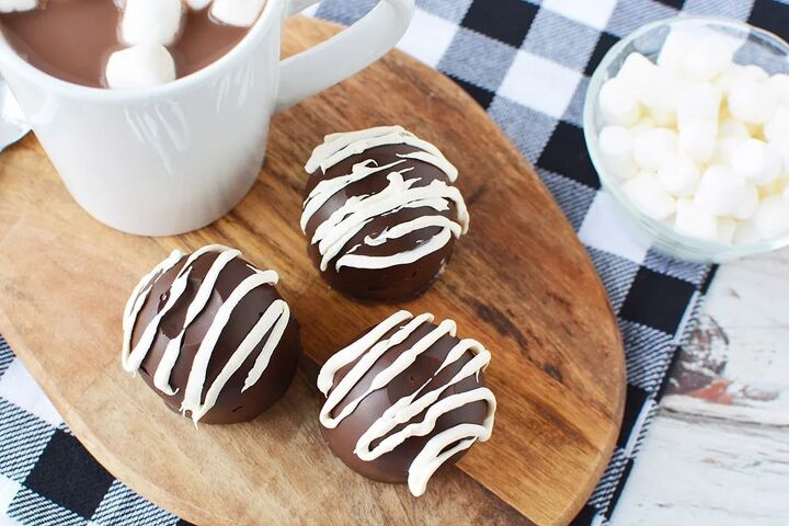 easy hot chocolate bombs, Hot chocolate bombs on a board next to a mug of hot cocoa and marshmallows