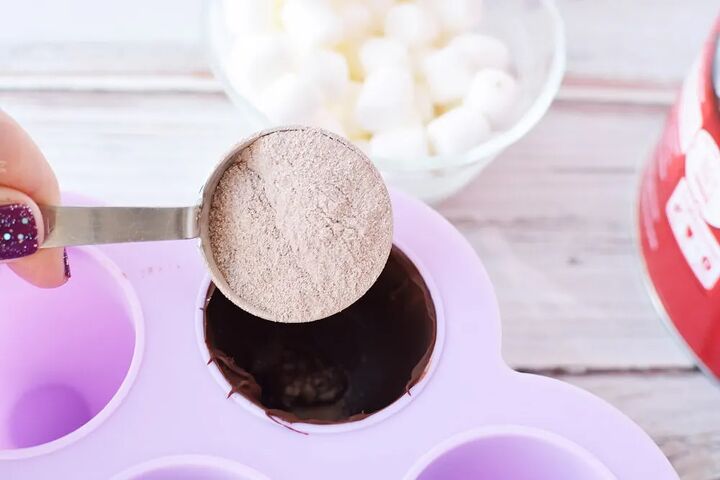 easy hot chocolate bombs, Pouring a scoop of hot chocolate into a candy mold
