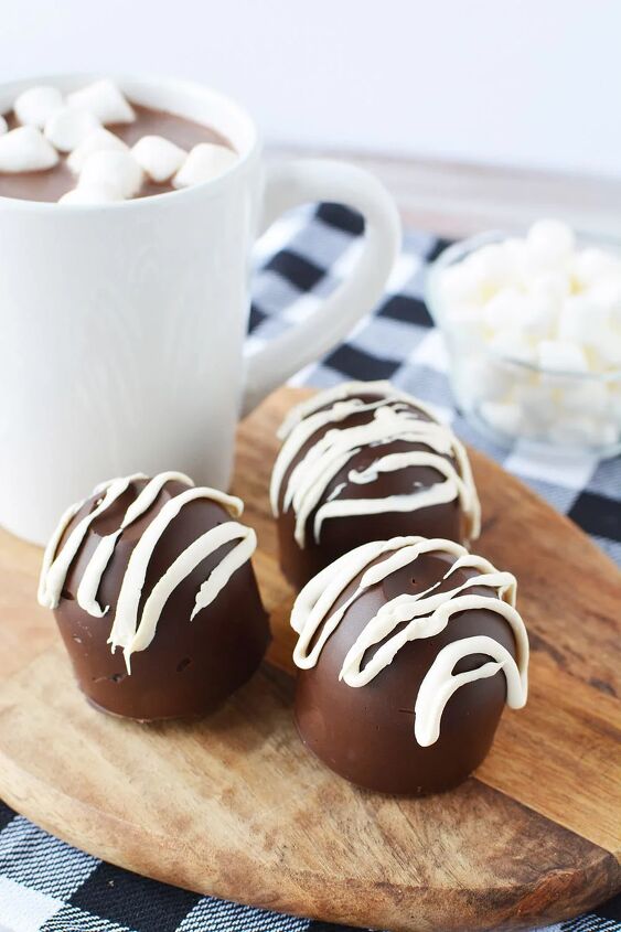 easy hot chocolate bombs, Three hot cocoa bombs on a board with a blue checked napkin on a table