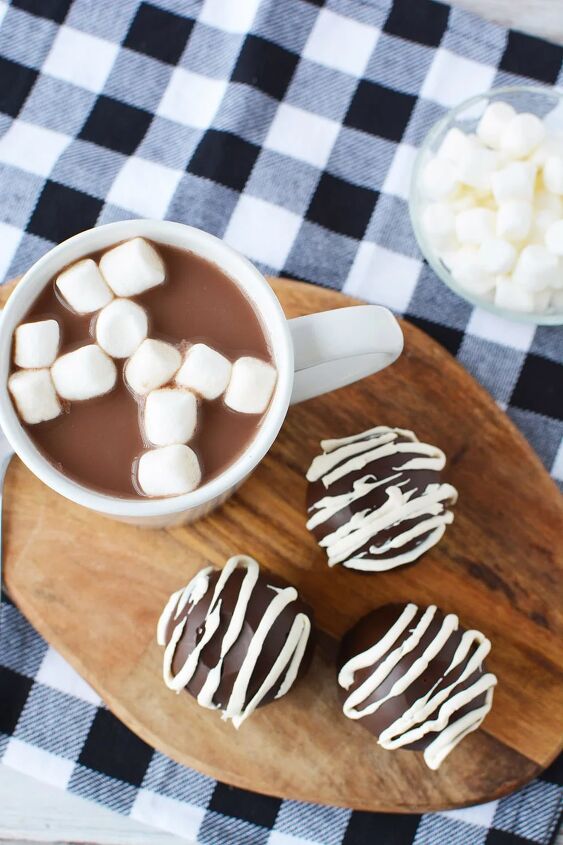 easy hot chocolate bombs, Three hot chocolate bombs next to a mug of hot chocolate with marshmallows in a bowl and a blue checked napkin