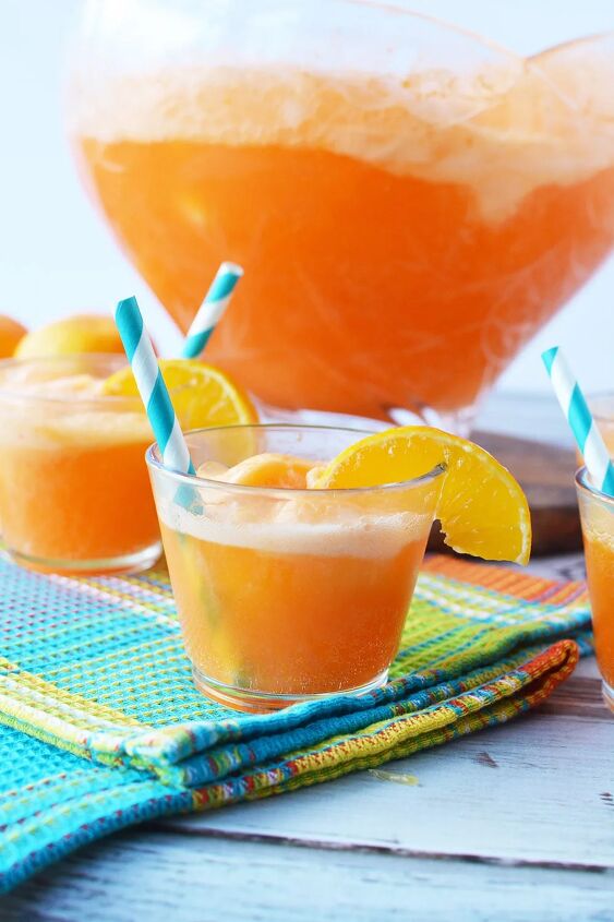 easy orange sherbet punch recipe, Glass of punch with bowl filled with orange punch