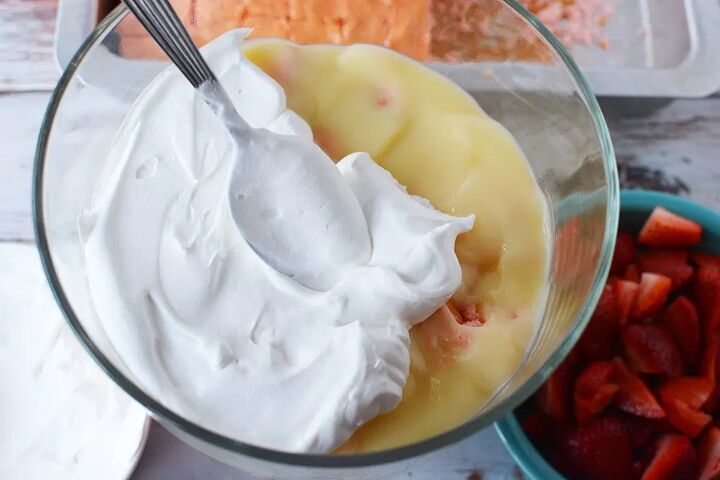 irresistible strawberry cheesecake trifle recipe, Putting whipped cream on top of pudding in a trifle
