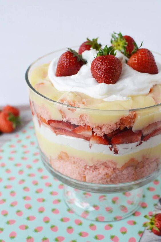irresistible strawberry cheesecake trifle recipe, A trifle bowl with layers of cake strawberries pudding and whipped cream topped with fresh berries