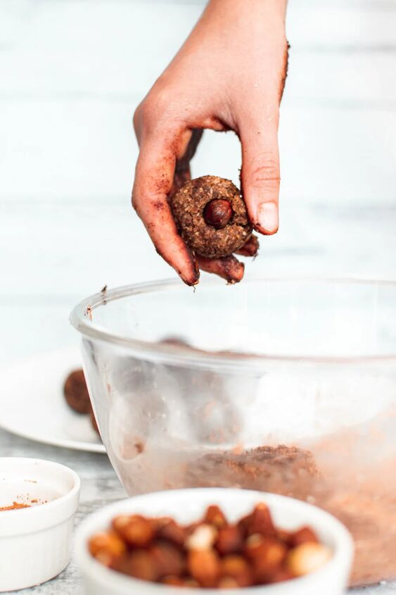homemade chocolate coconut date balls, Rolling date balls and placing a hazelnut into the center