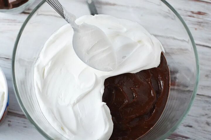 chocolaty chocolate trifle recipe, Spooning whipped cream on top of pudding in a trifle bowl