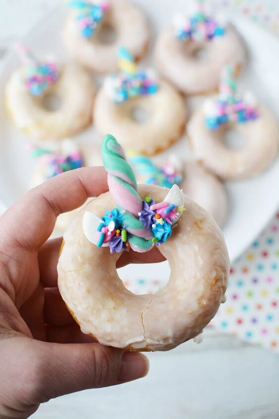 baked unicorn donut recipe with candy horns, Holding up a unicorn donut with full plate in the background