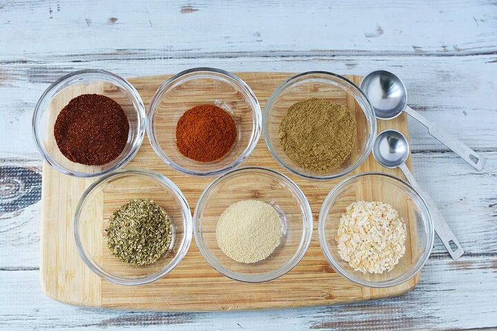 homemade taco seasoning mix, Bowls of spices for taco seasoning mix on a board next to measuring spoons