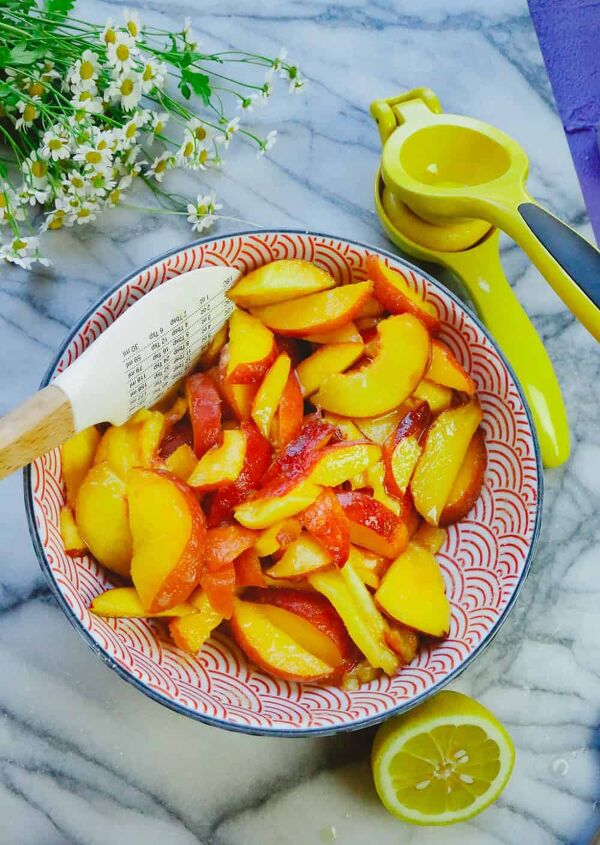honey peach pie homemade, bowl of fresh sliced peaches with a lemon juicer and a mixing spoon