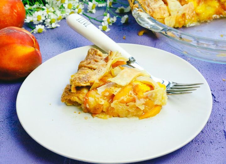 honey peach pie homemade, Slice of pie made with fresh peaches and honey served on a plate with a fork next to chamomile flowers