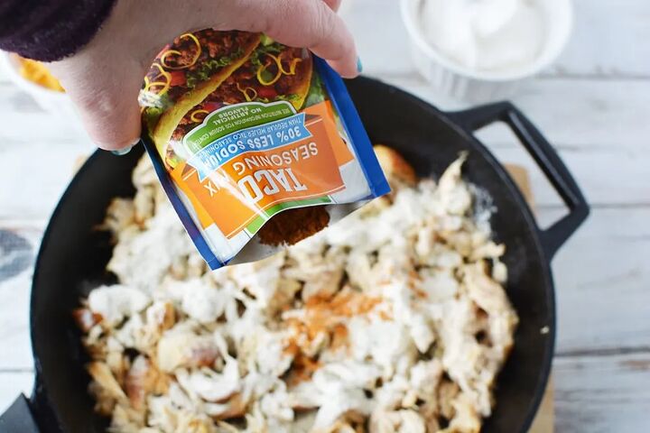 easy and flavorful chicken ranch tacos, Pouring taco seasoning onto shredded chicken in a skillet