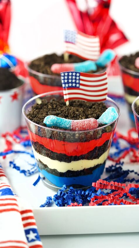 how to make red white and blue dessert dirt cups, up close view of red white and blue dirt pudding cups on a tray with american flag cupcake toppers and gummy worms