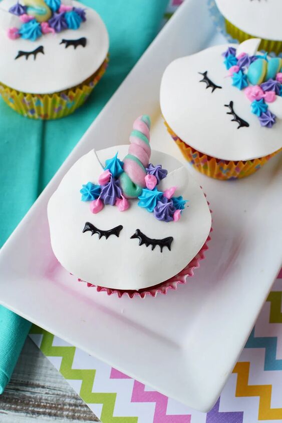adorable unicorn cupcakes with horns and eyes, Unicorn cupcakes with eyes ears and horns sitting on a tray on a table