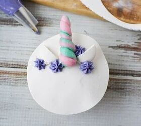 adorable unicorn cupcakes with horns and eyes, Decorating a unicorn cupcake with purple frosting