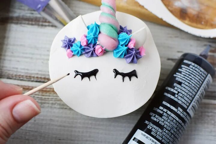 adorable unicorn cupcakes with horns and eyes, Drawing eyes on a unicorn cupcake with black frosting