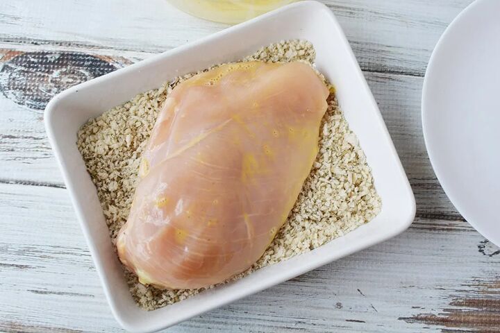easy parmesan crusted chicken recipe, Dipping egg washed chicken into a bowl of bread crumbs