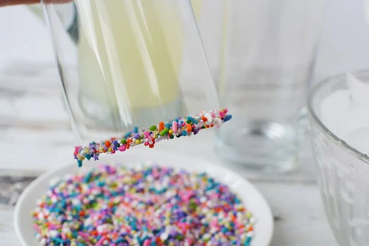 rainbow unicorn slush icy lemonade, Sprinkles around the lip of a glass above the plate of sprinkles