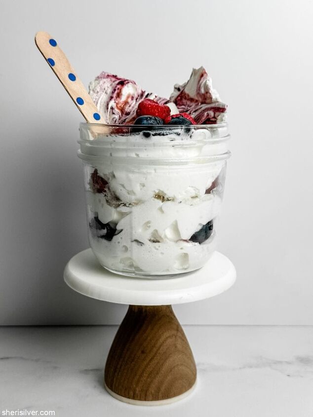 make this easy mixed berry meringue bark recipe for memorial day, glass jar filled with berries whipped cream and meringue bark on a mini cake stand