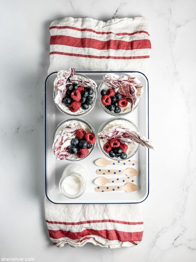 make this easy mixed berry meringue bark recipe for memorial day, glass jars filled with berries whipped cream and meringue bark set in an enamel tray atop a red and white kitchen towel