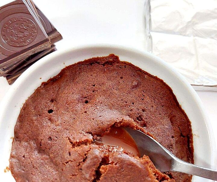 gooey chocolate mug cake that chocolate lovers need in their life, Gooey chocolate mug cake with a stack of chocolate squares on the side and a chocolate bar